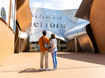 Zwei Personen stehen vor dem modernen Eingang des Marta Herford Museums mit gewellter Edelstahlfassade.
