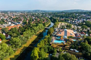 Luftaufnahme eines Freizeitkomplexes mit dem Fluss daneben, umgeben von Bäumen und einer Wohngegend.