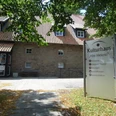 Kulturhaus "Alte Meierei" mit Sandsteinfassade, Schildern für Veranstaltungen und schattigem Eingangsbereich.