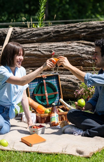Harsewinkel-Picknick-Teutoburger-Wald-Tourismus-Patrick-Gawandtka-064.jpg Ein Paar genießt ein sommerliches Picknick im Grünen, umgeben von Natur und Holzstämmen.