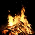 Osterfeuer Loderndes Osterfeuer mit brennenden Holzscheiten vor dunklem Hintergrund