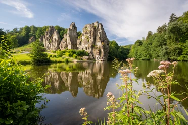 Horn-Bad Meinberg-Externsteine-Teutoburger-Wald-Tourismus-D-Ketz-055-CC-BY-SA.jpg Sandsteinfelsen spiegeln sich in einem malerischen See, umgeben von grüner Natur.
