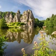 Horn-Bad Meinberg-Externsteine-Teutoburger-Wald-Tourismus-D-Ketz-055-CC-BY-SA.jpg Bizarr geformte Sandsteinfelsen spiegeln sich in einem malerischen See, umgeben von grüner Natur.