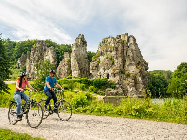 Zwei Radfahrer genießen eine Tour auf einem Schotterweg vor beeindruckenden Felsformationen.