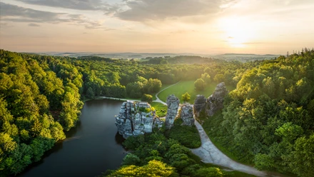 Luftaufnahme von den mystischen Externsteinen inmitten eines üppigen Waldes im Sonnenuntergang.