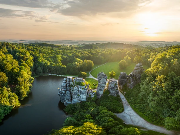 Horn-Bad Meinberg-Externsteine-Teutoburger-Wald-Tourismus-D-Ketz-002.jpg Luftaufnahme von den mystischen Externsteinen inmitten eines üppigen Waldes im Sonnenuntergang.