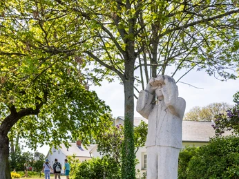 Mann mit Fernglas auf der Insel Wilhelmstein Skulptur eines Mannes mit Fernglas auf einem Sockel, umgeben von grünen Bäumen auf der Insel Wilhelmstein.