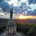 Hermannsdenkmal bei Detmold, eine Statue des Cheruskerfürsten Arminius, umgeben von Wald bei Sonnenuntergang.