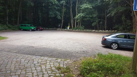 Wanderparkplatz Garrensee Sandparkplatz mit parkenden Autos. Im Hintergrund stehen Bäume