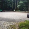 Wanderparkplatz Garrensee Sandparkplatz mit parkenden Autos. Im Hintergrund stehen Bäume