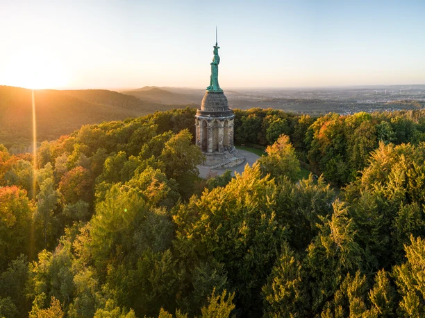 Das Hermannsdenkmal umgeben von Wäldern bei Sonnenuntergang, mit weitem Blick über die Landschaft.
