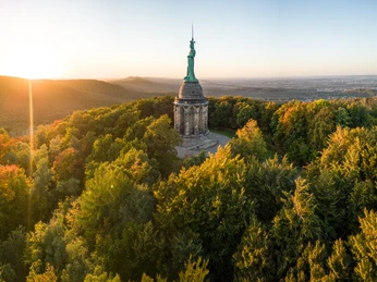 Detmold-Hermannsdenkmal-Teutoburger-Wald-Tourismus-D-Ketz-097.jpg Das Hermannsdenkmal umgeben von Wäldern bei Sonnenuntergang, mit weitem Blick über die Landschaft.