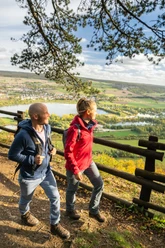 Hoexter-Rabenklippen-Teutoburger-Wald-Tourismus-D-Ketz-105.jpg Zwei Wanderer mit Rucksack genießen einen Panoramablick auf eine Flusslandschaft bei sonnigem Wetter.