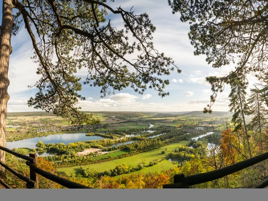 Panoramablick auf die Weser bei Höxter, umrahmt von Bäumen, im goldenen Licht des Spätnachmittags.