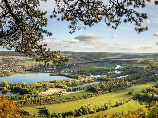 Hoexter-Rabenklippen-Teutoburger-Wald-Tourismus-D-Ketz-110-CC-BY-SA.jpg Panorama einer idyllischen Flusslandschaft im Sommer mit Wald, Fluss und hügeligem Hintergrund.