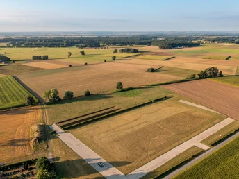 Luftaufnahme von weitläufigen, goldenen und grünen Feldern unter blauem Himmel in Oberösterreich.