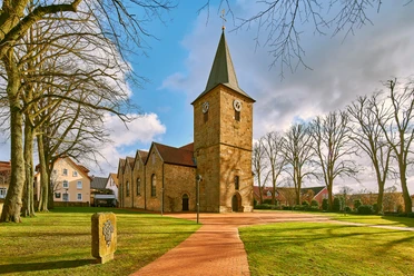 Ehemalige Kirche Hagen Außenansicht Großflächiger Platz mit Kirche im Sonnenschein, umgeben von Bäumen und historischen Gebäuden.