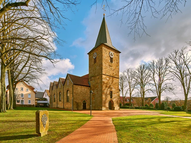 Ehemalige Kirche Hagen Außenansicht Großflächiger Platz mit Kirche im Sonnenschein, umgeben von Bäumen und historischen Gebäuden.