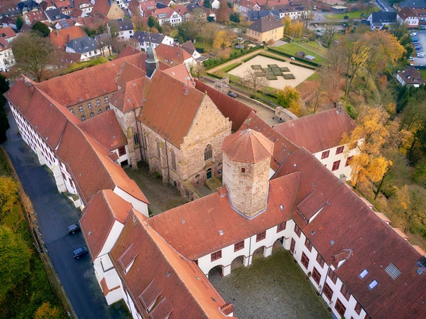 Luftaufnahme eines historischen Klosterkomplexes mit roten Ziegeldächern und Herbstbäumen.