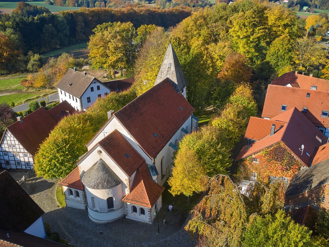 Luftaufnahme der St.Urban Kirche in Bissendorf, umgeben von herbstlich gefärbten Bäumen und Gebäuden.