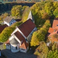 Luftaufnahme der St.Urban Kirche in Bissendorf, umgeben von herbstlich gefärbten Bäumen und Gebäuden.