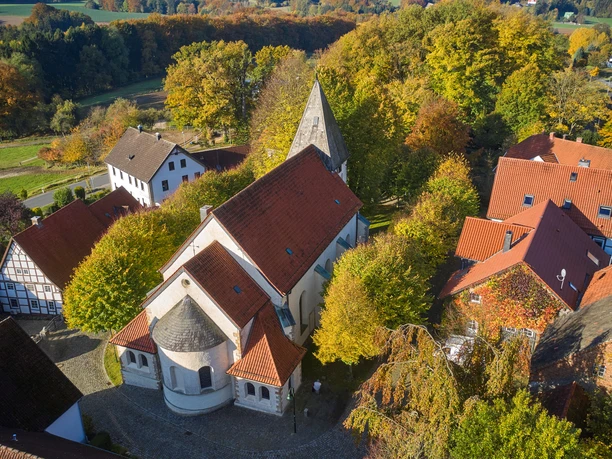 Luftaufnahme der St.Urban Kirche in Bissendorf, umgeben von herbstlich gefärbten Bäumen und Gebäuden.