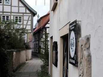 Braugasse 2 Eine enge Gasse mit Fachwerkhäusern und einem nostalgischen Laternenhalter an einer weiß verputzten Wand.