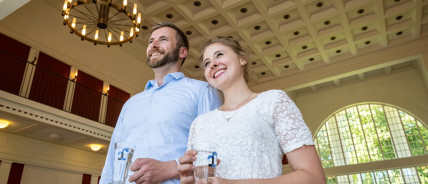 Bad Oeynhausen-Kurpark-Teutoburger-Wald-Tourismus-D-Ketz-286.jpg Ein Paar steht im Kurhaus Bad Oeynhausen und hat zwei Gläser mit Wasser in der Hand