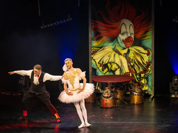 Bad Oeynhausen-GOP-Teutoburger-Wald-Tourismus-D-Ketz-096.jpg Zwei Zirkusperformer, als Clown und Ballerina verkleidet, tanzen auf einer Bühne vor einem Clownsbild.