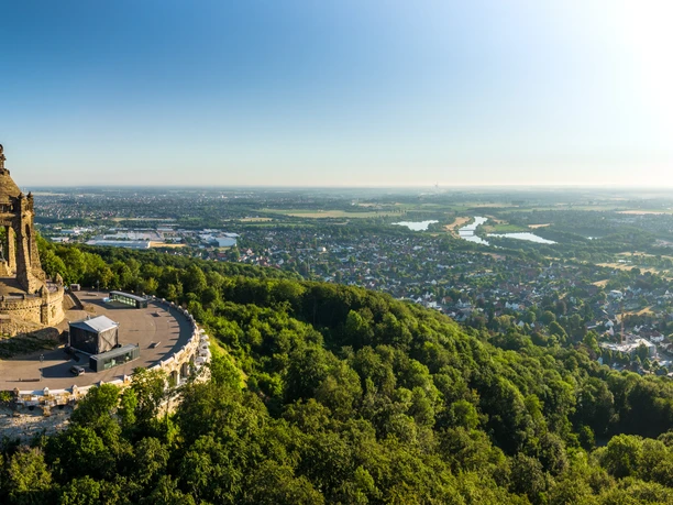 Panorama des Kaiser-Wilhelm-Denkmals, umgeben von üppigen Wäldern, mit weitem Blick auf die Stadt.
