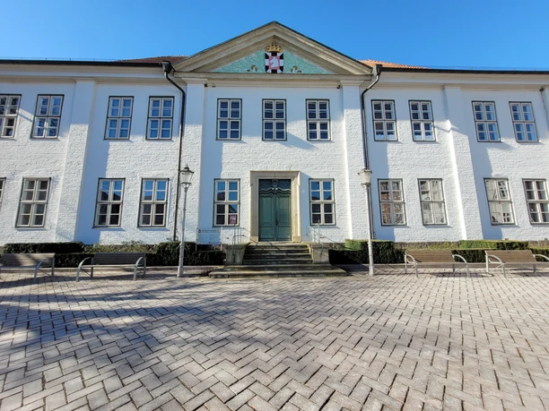 Kreisarchiv2_Silvana Dust_20230228.jpg Das Kreisarchiv Ratzeburg von außen, weißes Gebäude mit Wappen oben im Vorsprung