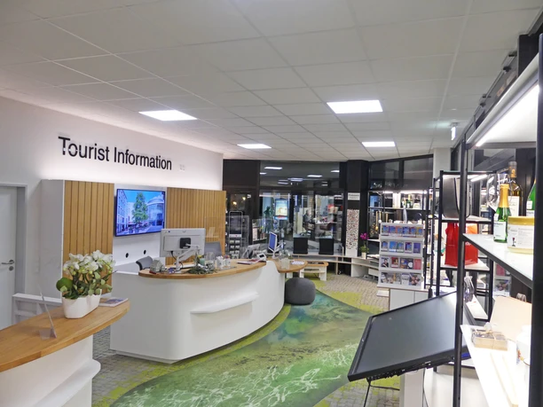 Heller, moderner Raum der Tourist Information mit Info-Theke und Regalen voller Broschüren und Karten.
