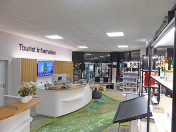 Tourist Information Paderborn Heller, moderner Raum der Tourist Information mit Info-Theke und Regalen voller Broschüren und Karten.
