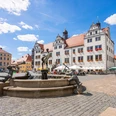Torgau Markt Brunnen auf dem Marktplatz von Torgau vor historischen Gebäuden bei blauem Himmel.