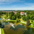 Kurpark Bad Salzuflen Der Bild zeigt einen weitläufigen Park mit grünen Wiesen, einem Teich und einem zentralen Wasserbrunnen.