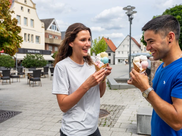 Bueren_Altstadt_Teutoburger-Wald-Tourismus-Patrick-Gawandtka-072.jpg <p>Ein lächelndes Paar genießt Eis auf einem belebten Stadtplatz bei sonnigem Wetter.</p>