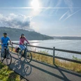 BadWuennenberg–Aabachtalsperre-Teutoburger-Wald-Tourismus-Patrick-Gawandtka-023.jpg Two cyclists ride relaxed in the morning along a calm lake under a clear blue sky.