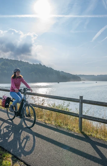 BadWuennenberg–Aabachtalsperre-Teutoburger-Wald-Tourismus-Patrick-Gawandtka-023.jpg Two cyclists ride relaxed in the morning along a calm lake under a clear blue sky.