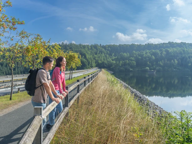 BadWuennenberg–Aabachtalsperre-Teutoburger-Wald-Tourismus-Patrick-Gawandtka-026.jpg <p>Zwei Menschen genießen den Ausblick von einem Damm auf einen ruhigen, von Bäumen umgebenen See.</p>
