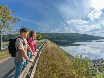 BadWuennenberg–Aabachtalsperre-Teutoburger-Wald-Tourismus-Patrick-Gawandtka-027.jpg Zwei Personen blicken an einem sonnigen Tag auf einen großen See, umgeben von grünen Bäumen.Op een zonnige dag kijken twee mensen uit over een groot meer omringd door groene bomen.Two people look out over a large lake surrounded by green trees on a sunny day.