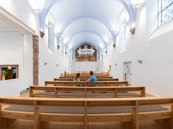 Beverungen-Abtei-Herstelle-Teutoburger-Wald-Tourismus-A-Röser-055.jpg <p>Blick in den hellen, modernen Kirchenraum mit Holzbankreihen, einem Paar im Zentrum und gewölbter Decke.</p><p>Zicht op het heldere, moderne kerkinterieur met rijen houten banken, een echtpaar in het midden en een gewelfd plafond.<p>View of the bright, modern church interior with rows of wooden pews, a couple in the center and vaulted ceiling.</p>