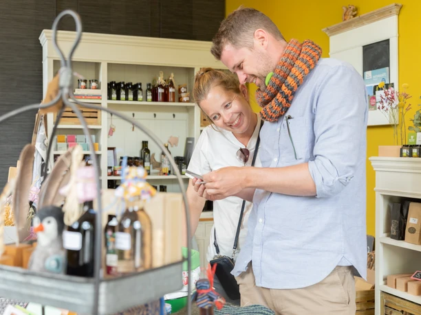 Ein Paar erkundet lächelnd ein Geschäft mit regionalen Produkten und Handwerksartikeln.