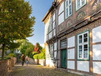 Fachwerkhaus in Blomberg mit dekorierten Balken, gepflasterte Straße und Spaziergänger im Herbstlicht.