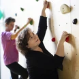 Kletterwand MZG Bad Lippspringe Zwei Personen klettern an einer Indoor-Kletterwand, konzentriert und fokussiert in der Bewegung.