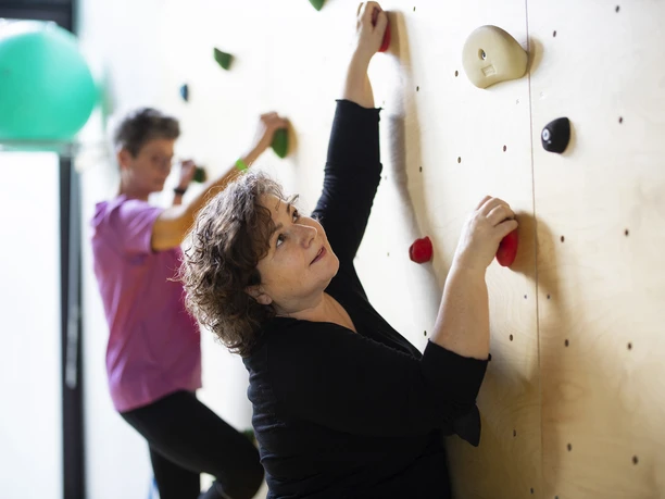 Kletterwand MZG Bad Lippspringe Zwei Personen klettern an einer Indoor-Kletterwand, konzentriert und fokussiert in der Bewegung.