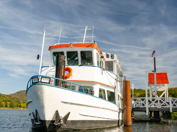 Schieder-Schwalenberg-Schiedersee-Teutoburger-Wald-Tourismus-D-Ketz-075.jpg Ein weißes Ausflugsschiff mit orangefarbenem Dach liegt an einem sonnigen Tag an einem Steg vor Anker.