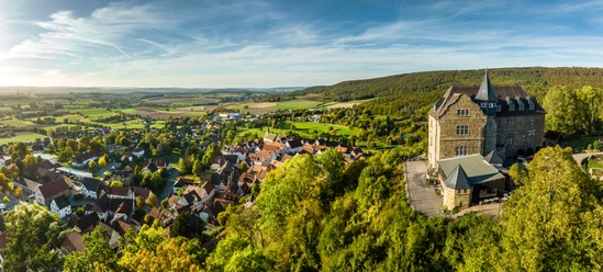 Schieder-Schwalenberg-Grafenblick-Teutoburger-Wald-Tourismus-D-Ketz-118-CC-BY-SA.jpg Luftaufnahme eines malerischen Dorfes in hügeliger Landschaft mit historischem Schloss am rechten Bildrand.