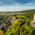 Schieder-Schwalenberg-Grafenblick-Teutoburger-Wald-Tourismus-D-Ketz-118-CC-BY-SA.jpg Luftaufnahme eines malerischen Dorfes in hügeliger Landschaft mit historischem Schloss am rechten Bildrand.