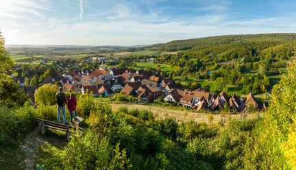 Schieder-Schwalenberg-Grafenblick-Teutoburger-Wald-Tourismus-D-Ketz-123.jpg Ein Panoramablick auf ein idyllisches Dorf umgeben von grünen Hügeln und dicht bewaldeter Landschaft.