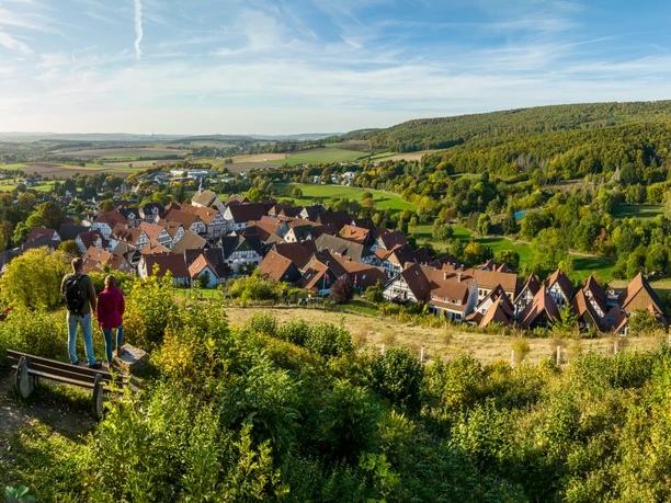 Schieder-Schwalenberg-Grafenblick-Teutoburger-Wald-Tourismus-D-Ketz-123.jpg Ein Panoramablick auf ein idyllisches Dorf umgeben von grünen Hügeln und dicht bewaldeter Landschaft.